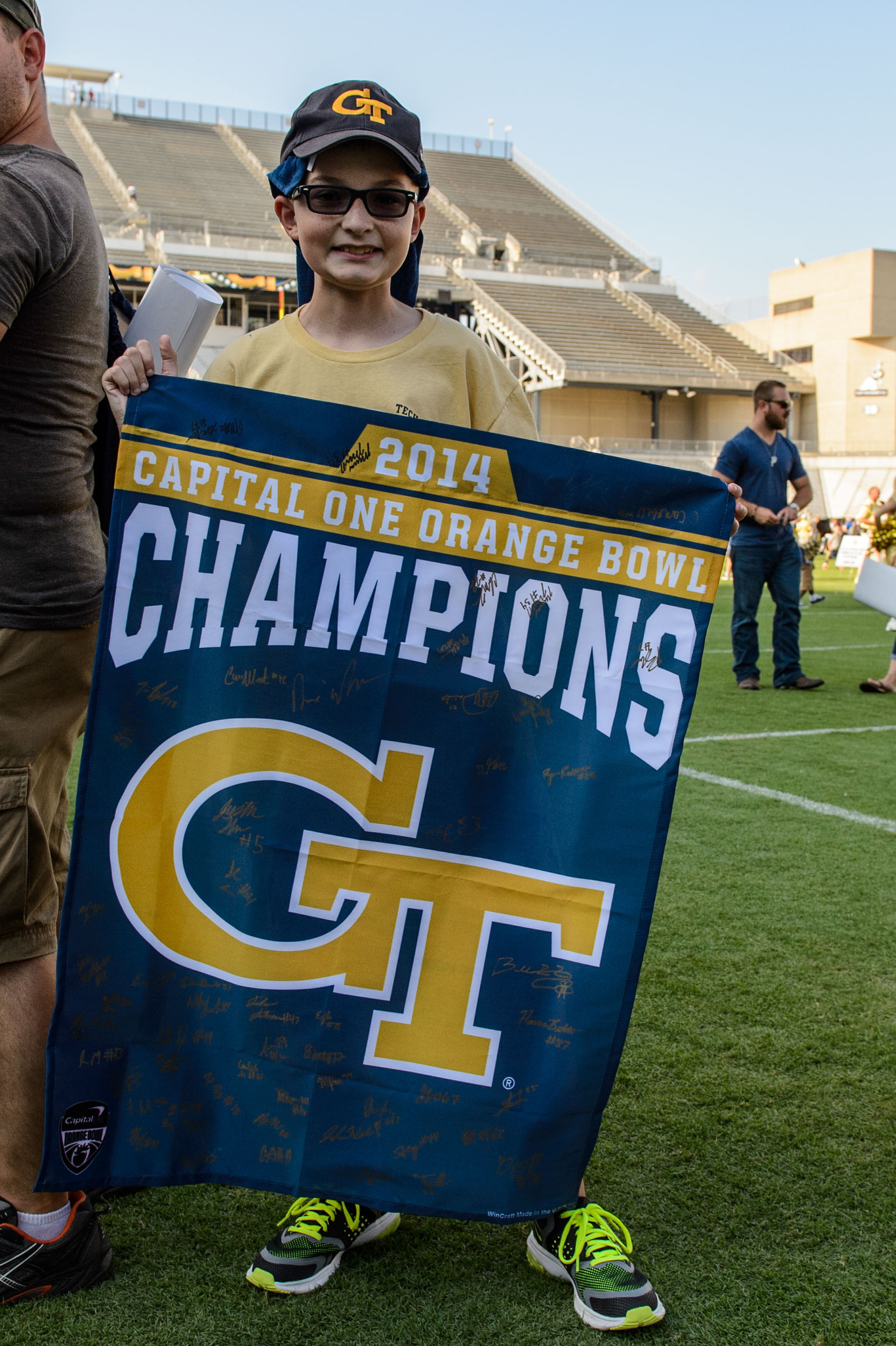A young fan waits with his Orange Bowl Champions banner
