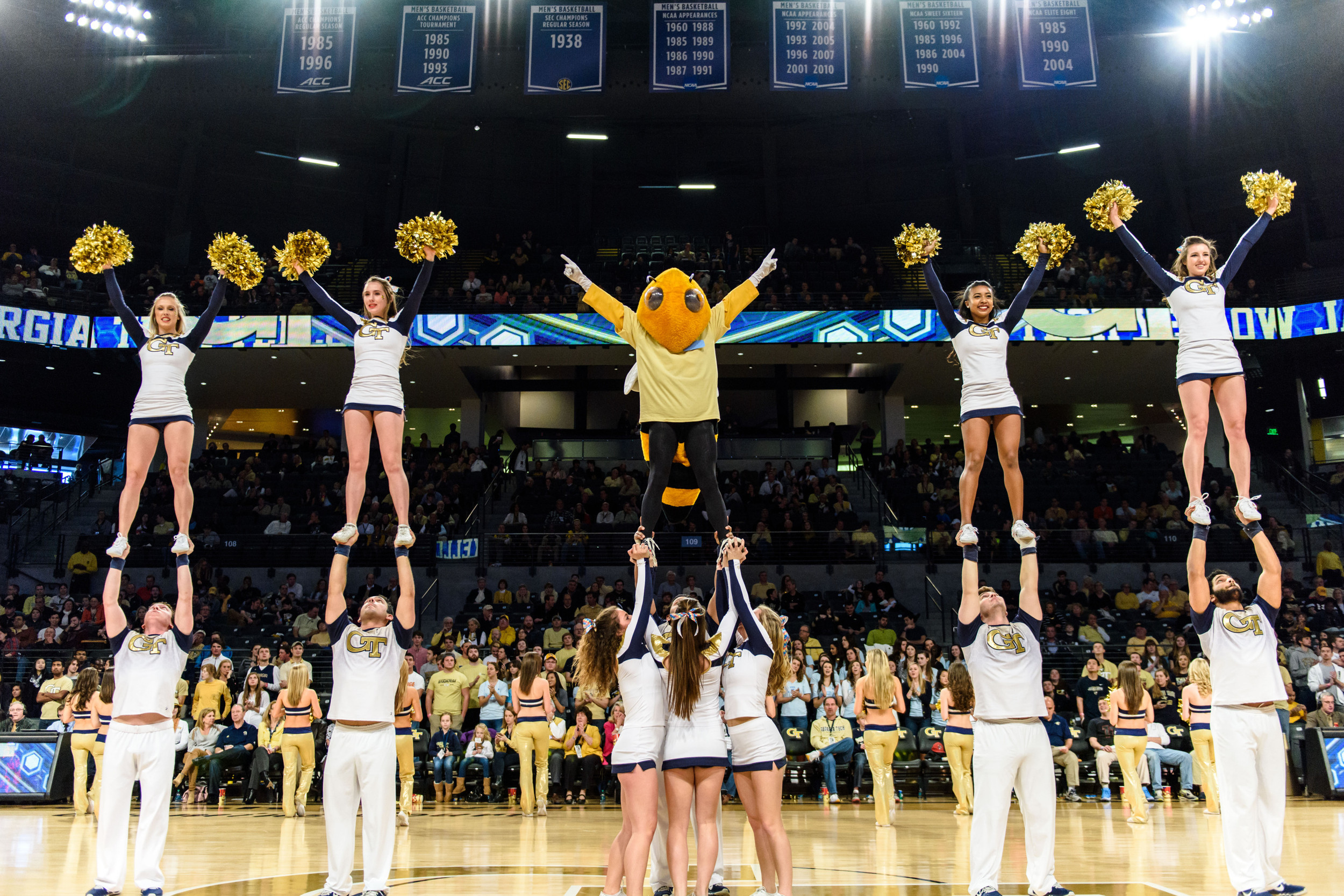 Georgia Tech Cheerleading performs a stunt with Buzz, who is wearing a t-shirt for Coaches Powering Forward For Autism