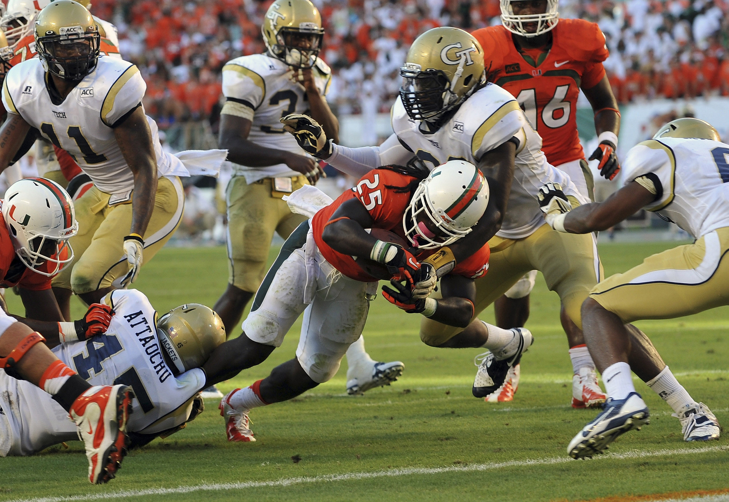 Oct 5, 2013; Miami Gardens, FL, USA; Miami Hurricanes running back Dallas Crawford (25) scores a touchdown as Georgia Tech Yellow Jackets defensive end Emmanuel Dieke (93) defends the play during the second half at Sun Life Stadium. Mandatory Credit: Steve Mitchell-USA TODAY Sports