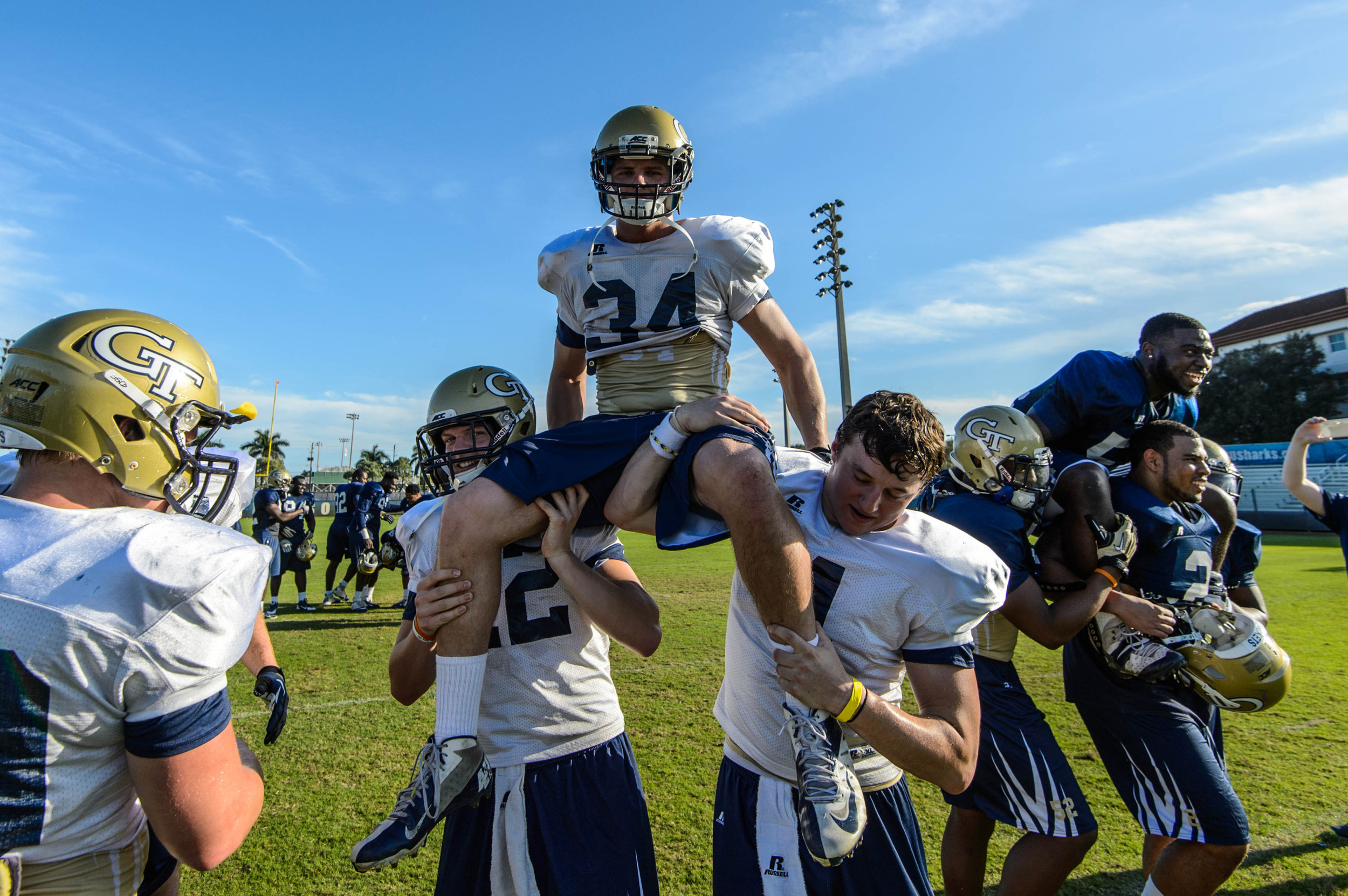 Chase Martenson (12) and Brady Swilling (4) carry senior Matt Connors (34) off the field after his final practice as a Yellow Jacket, while senior Quayshawn Nealy (54) is carried off by his fellow linebackers in the background