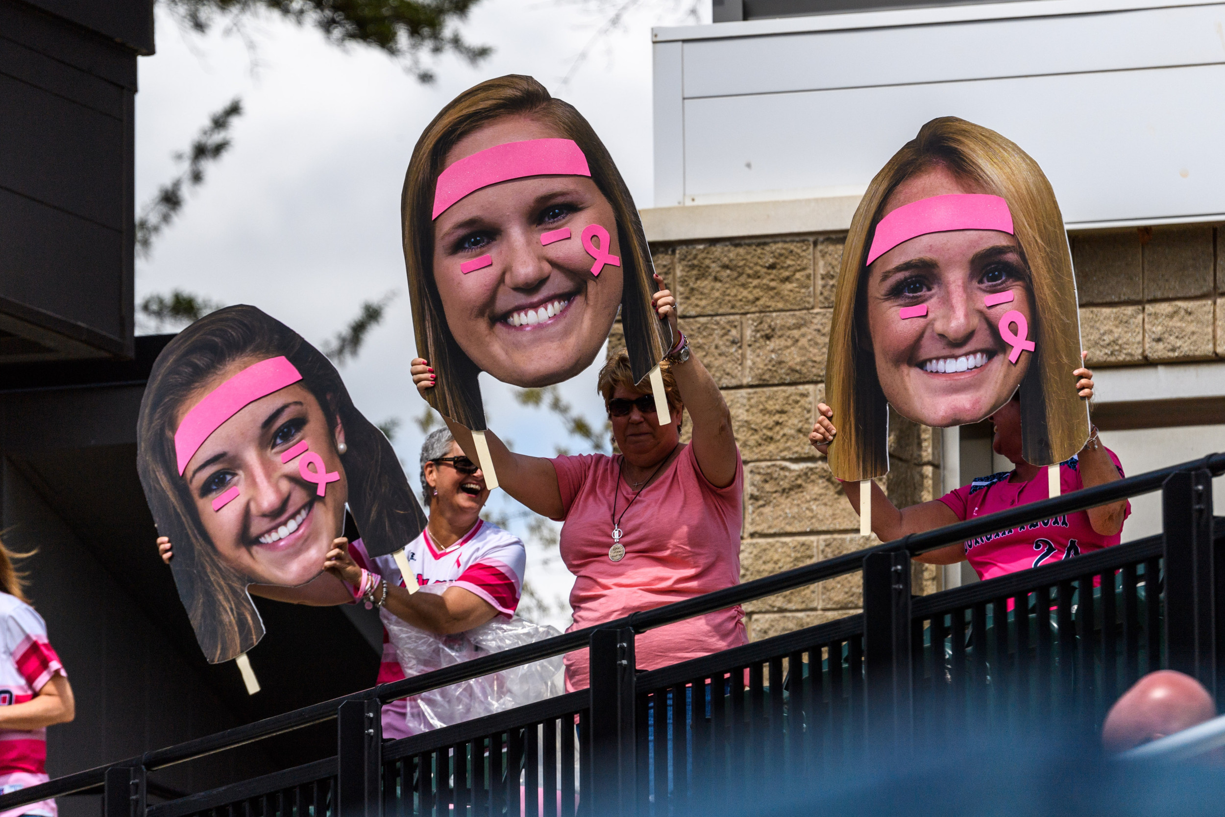 The pom-pom moms hold up decorated big heads of their daughters