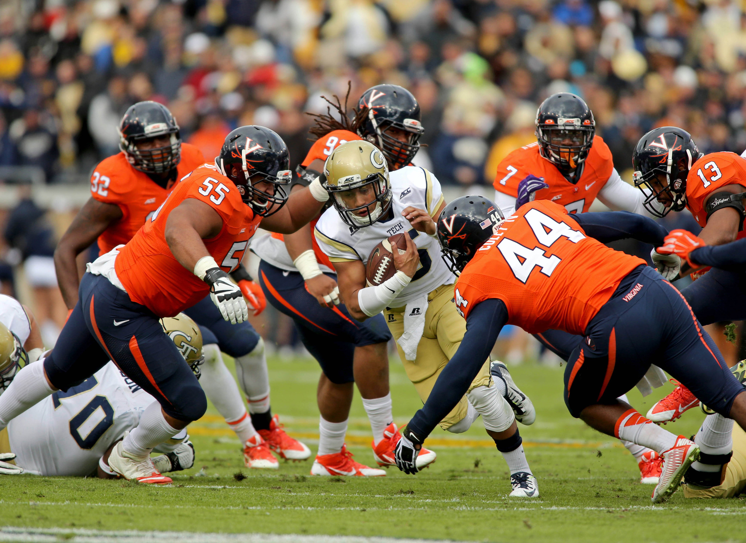 Georgia Tech Yellow Jackets quarterback Justin Thomas (5) runs through a hole as Virginia Cavaliers defensive tackle David Dean (55) and linebacker Henry Coley (44) make the tackle on Thomas in the first quarter of their game at Bobby Dodd Stadium. Jason Getz-USA TODAY Sports