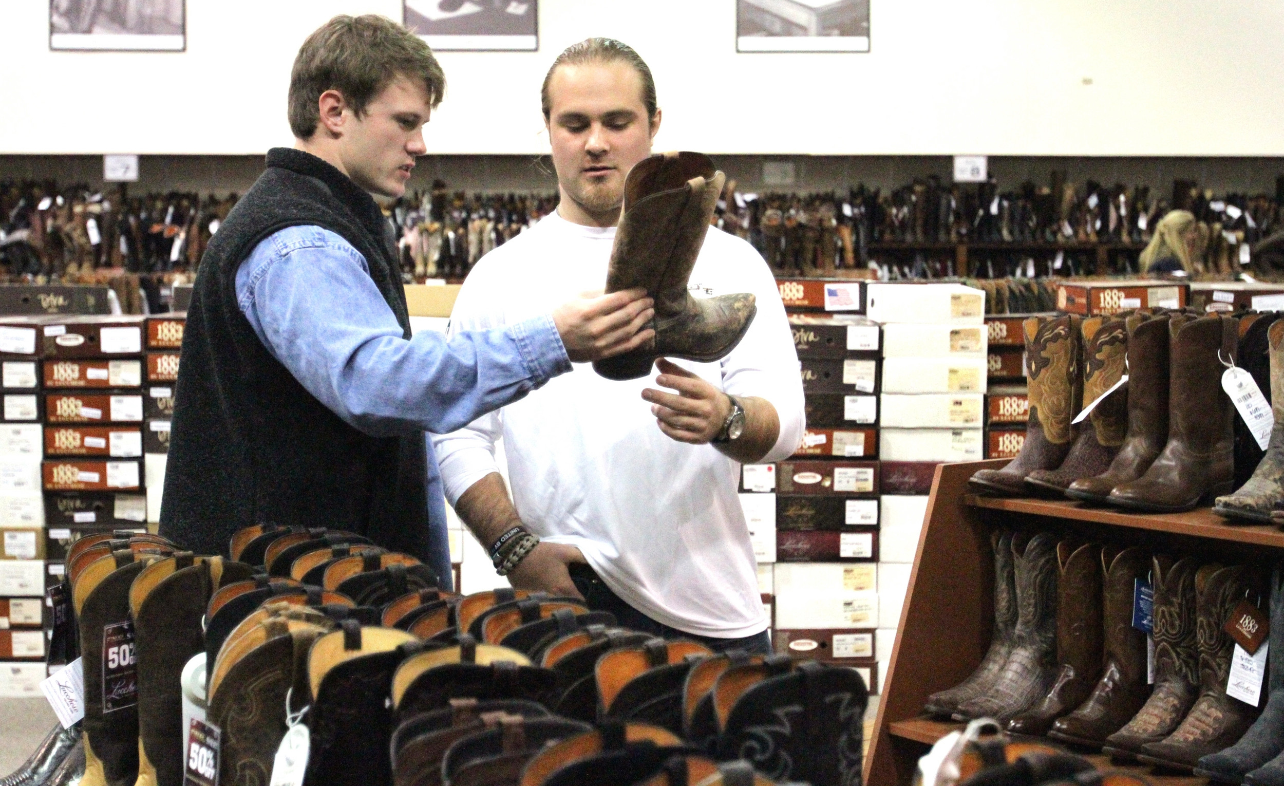 Georgia Tech linebacker Corey Alford, right, shows a pair of boots to fellow linebacker Ryan Sparlin during a team visit to the Luccese boot store Saturday, Dec. 29, 2012, in El Paso, Texas. Some of the team's players were taken to the boot store for their chance to take home a pair of cowboy boots. (AP Photo/El Paso Times, Rudy Gutierrez)