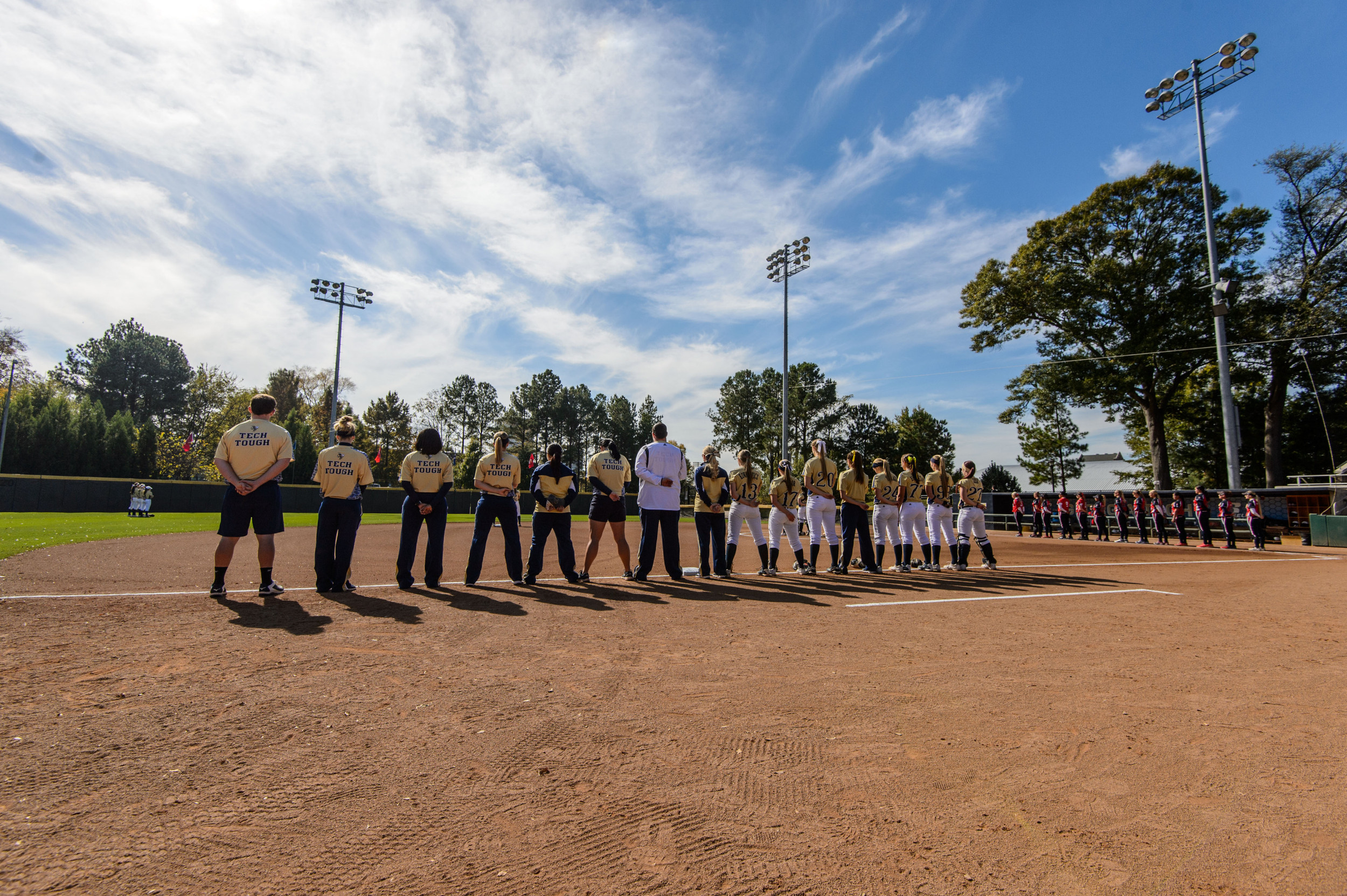 The teams line the bases for the national anthem