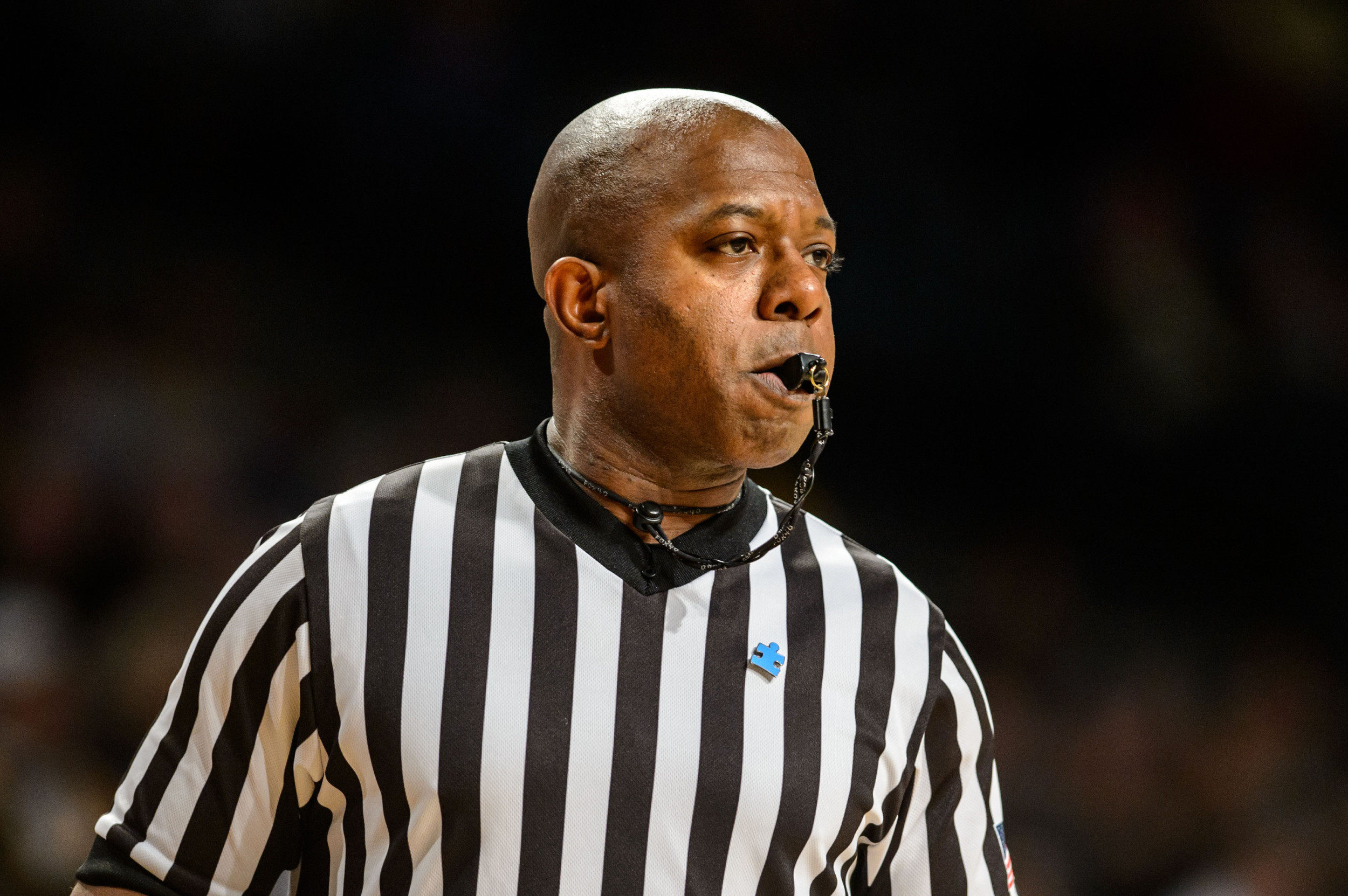 An official wears the blue, puzzle-piece pin for Coaches Powering Forward For Autism