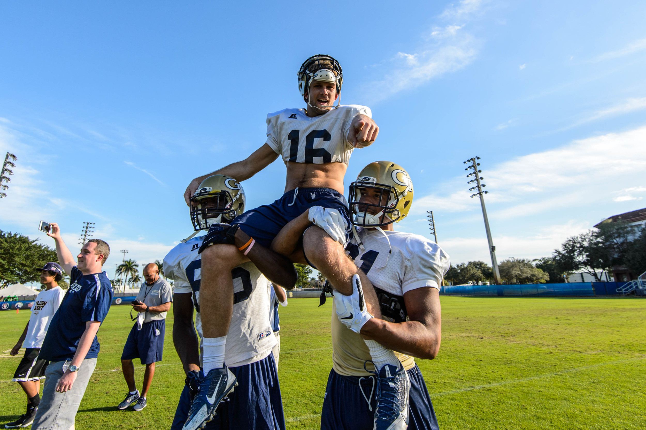 Ricky Jeune (81) & Antonio Messick (86) carry senior Corey Dennis (16) off the field after his final practice as a Yellow Jacket