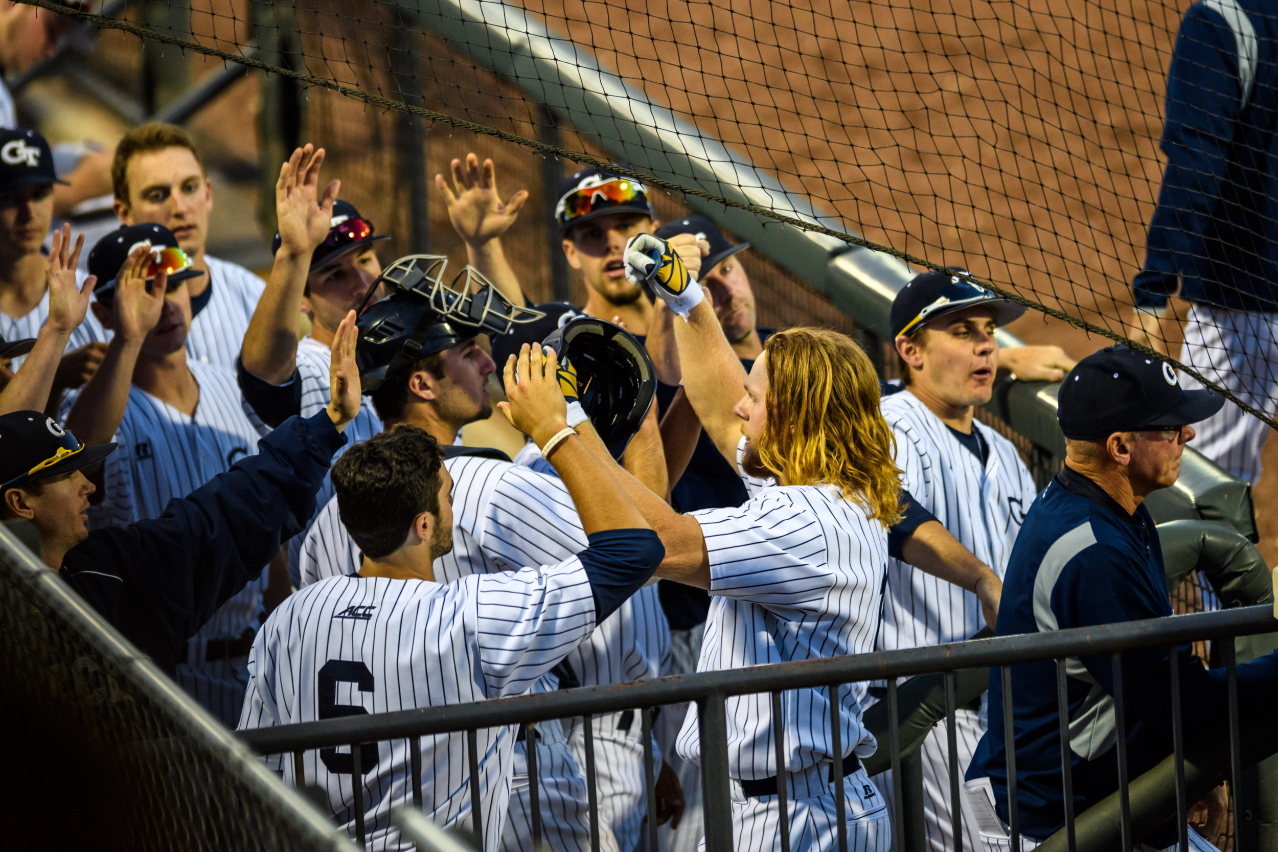 Coleman Poje (16) is congratulated by the team on returning to the dugout after his home run