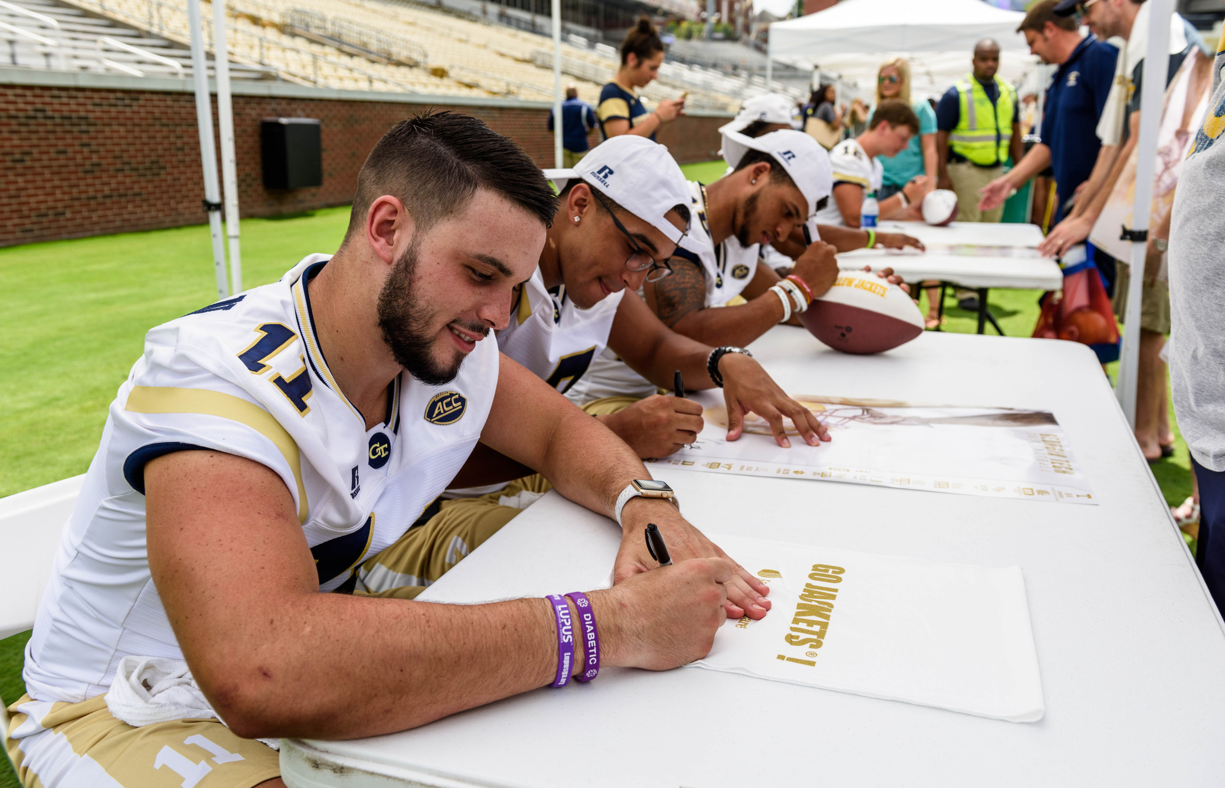 Quarterbacks Matthew Jordan (left), Lucas Johnson (center), and Tobias Oliver (right) sign autographs at Fan Day