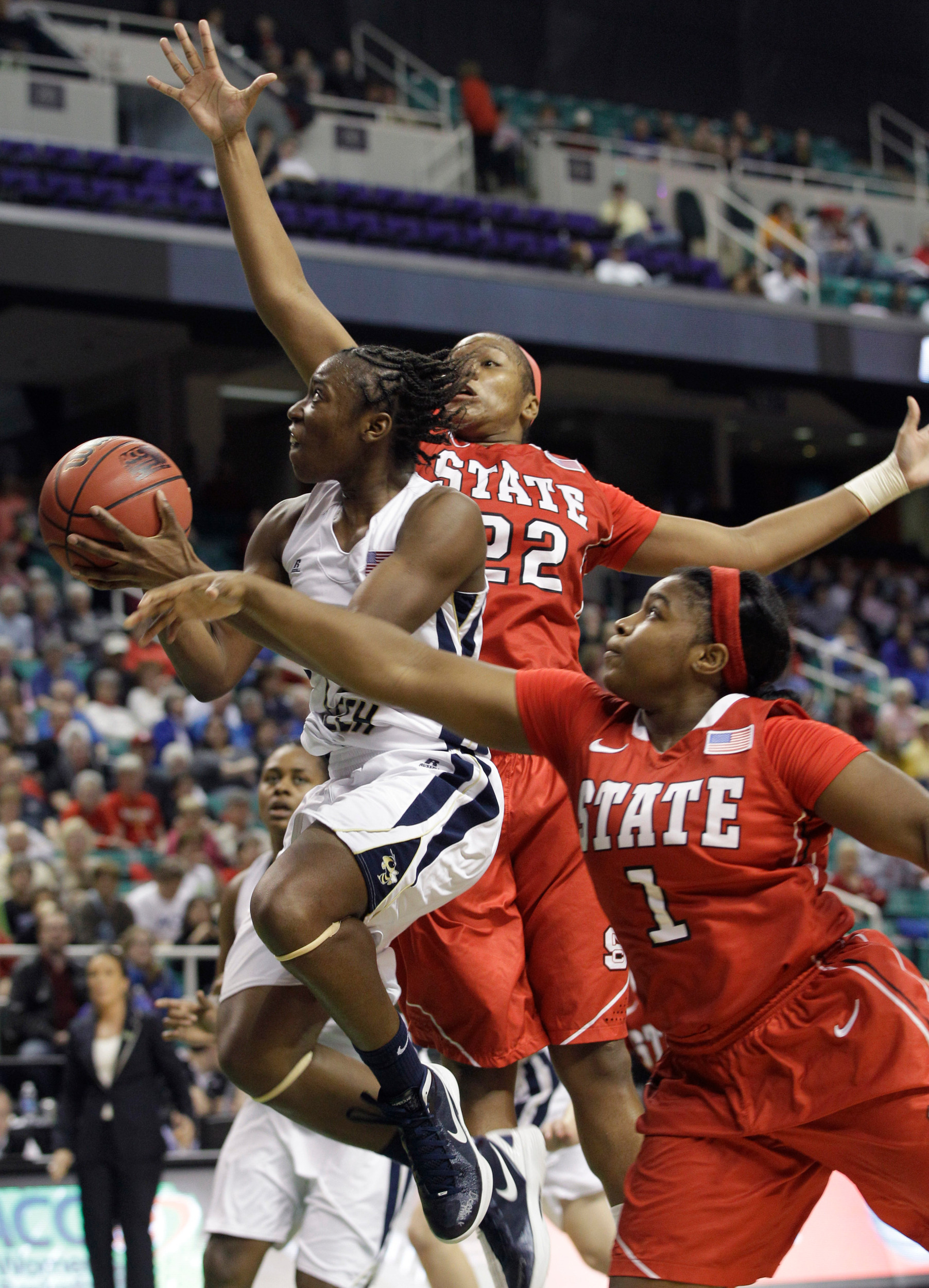Tyaunna Marshall drives between North Carolina State's Bonae Holston and Myisha Goodwin-Coleman. (AP Photo/Chuck Burton)