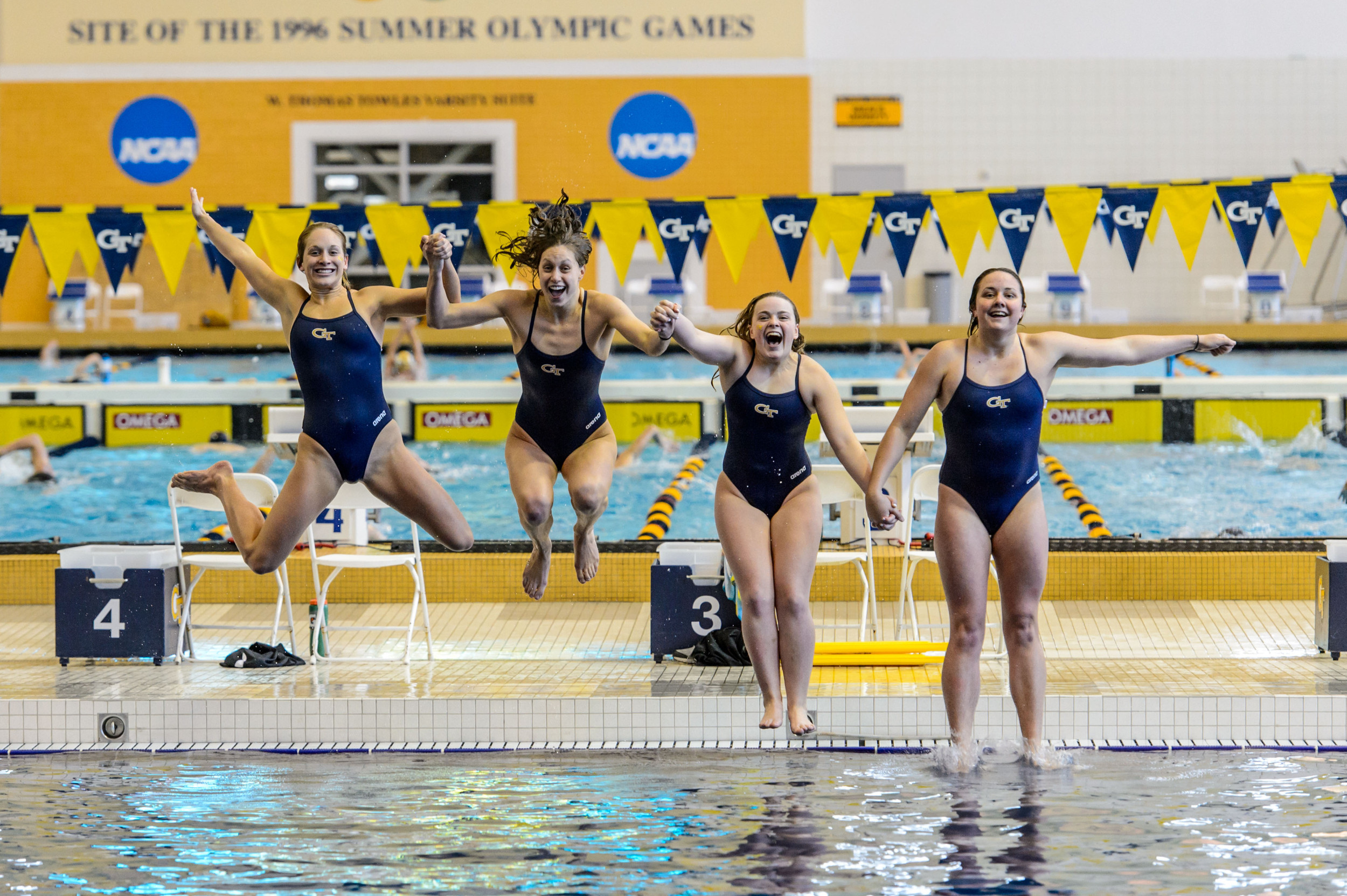 Seniors Kate Brandus, Kelsey Maloney, Catherine Richards, and Kate Woolbright leap into the pool at the end of the meet