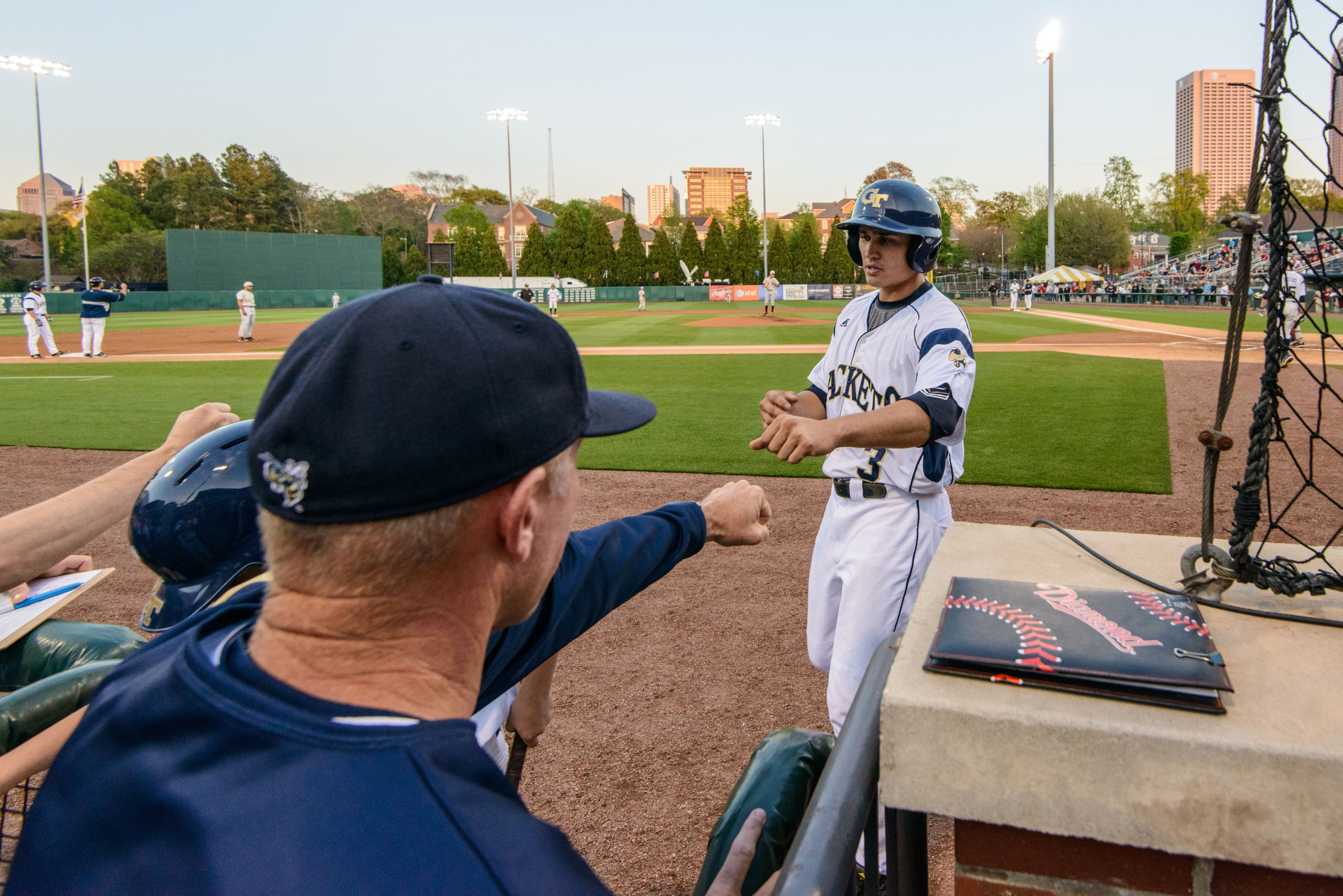 Mott Hyde (3) is welcomed back to the dugout by Coach Hall after scoring a run