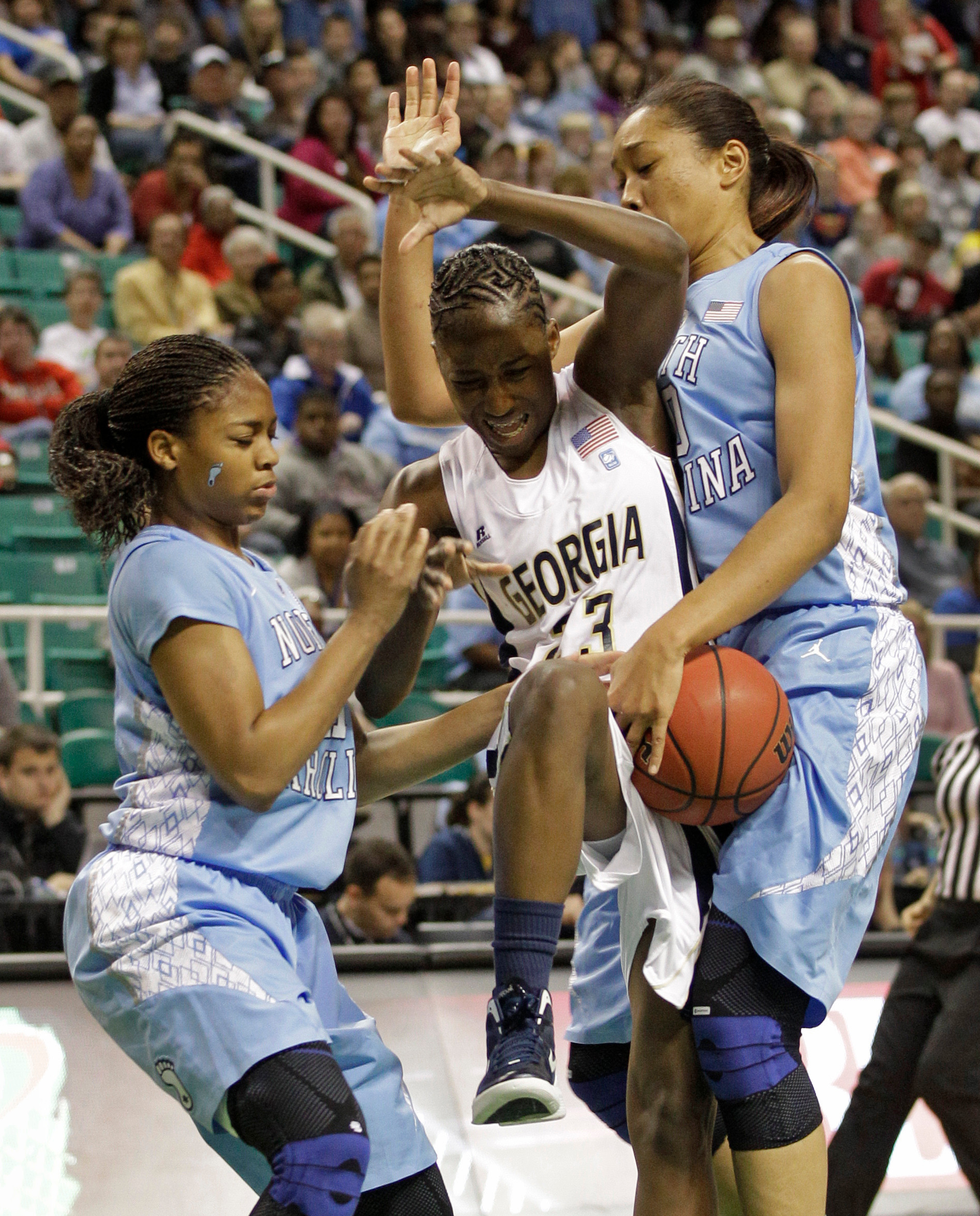 Sydney Wallace is fouled as she drives between North Carolina's Chay Shegog and Brittany Rountree. (AP Photo/Chuck Burton)