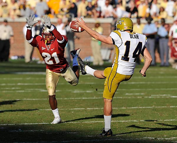 Scott Blair (14) gets the punt off under pressure from FSU's Patrick Robinson. Photo by LensEffects