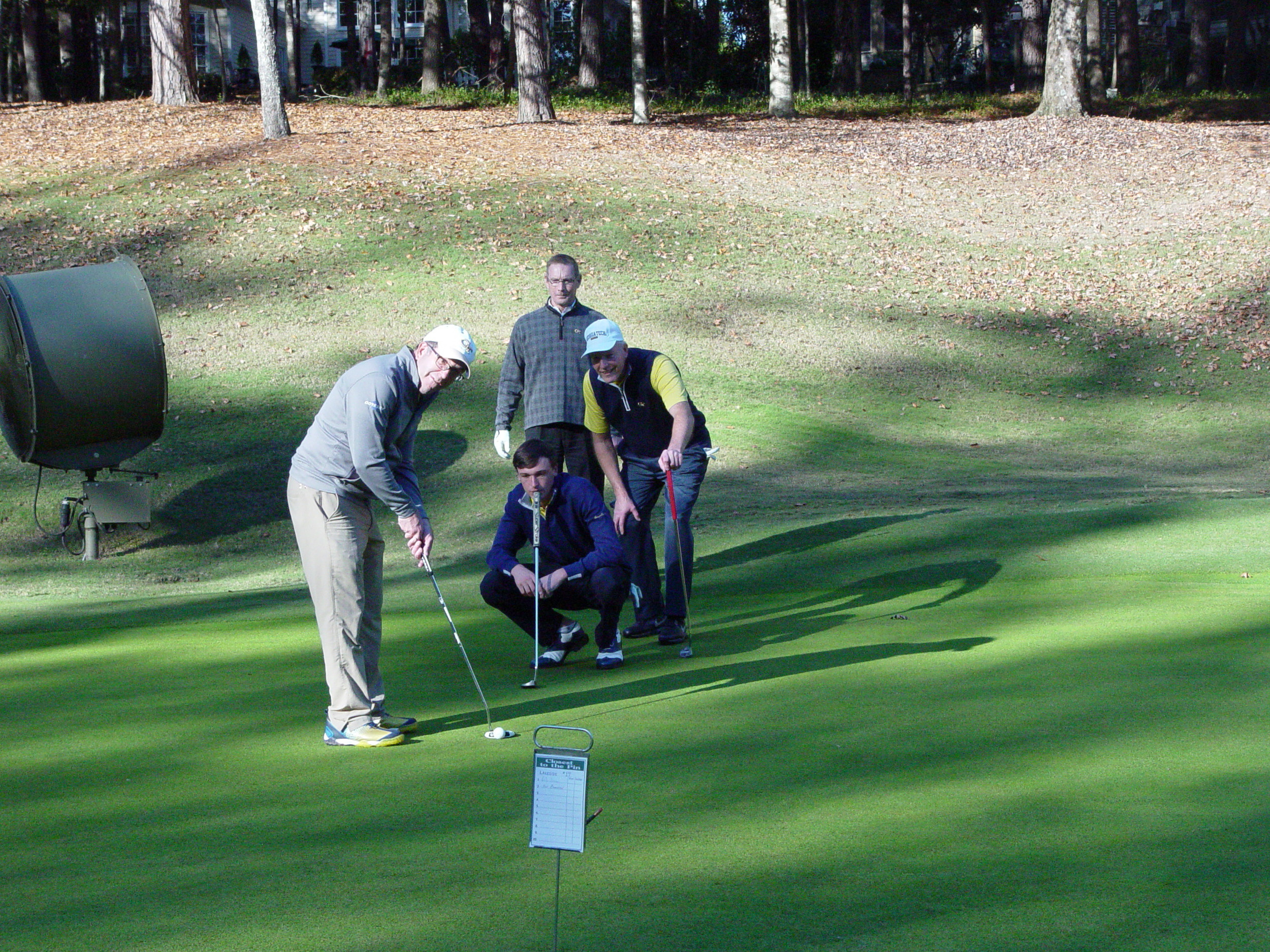 Shawn Fowler, AD Todd Stansbury and Sam Grice watch Luke Schninederjans line up a putt at the Ramblin' Wreck Cup, November 12, 2017
