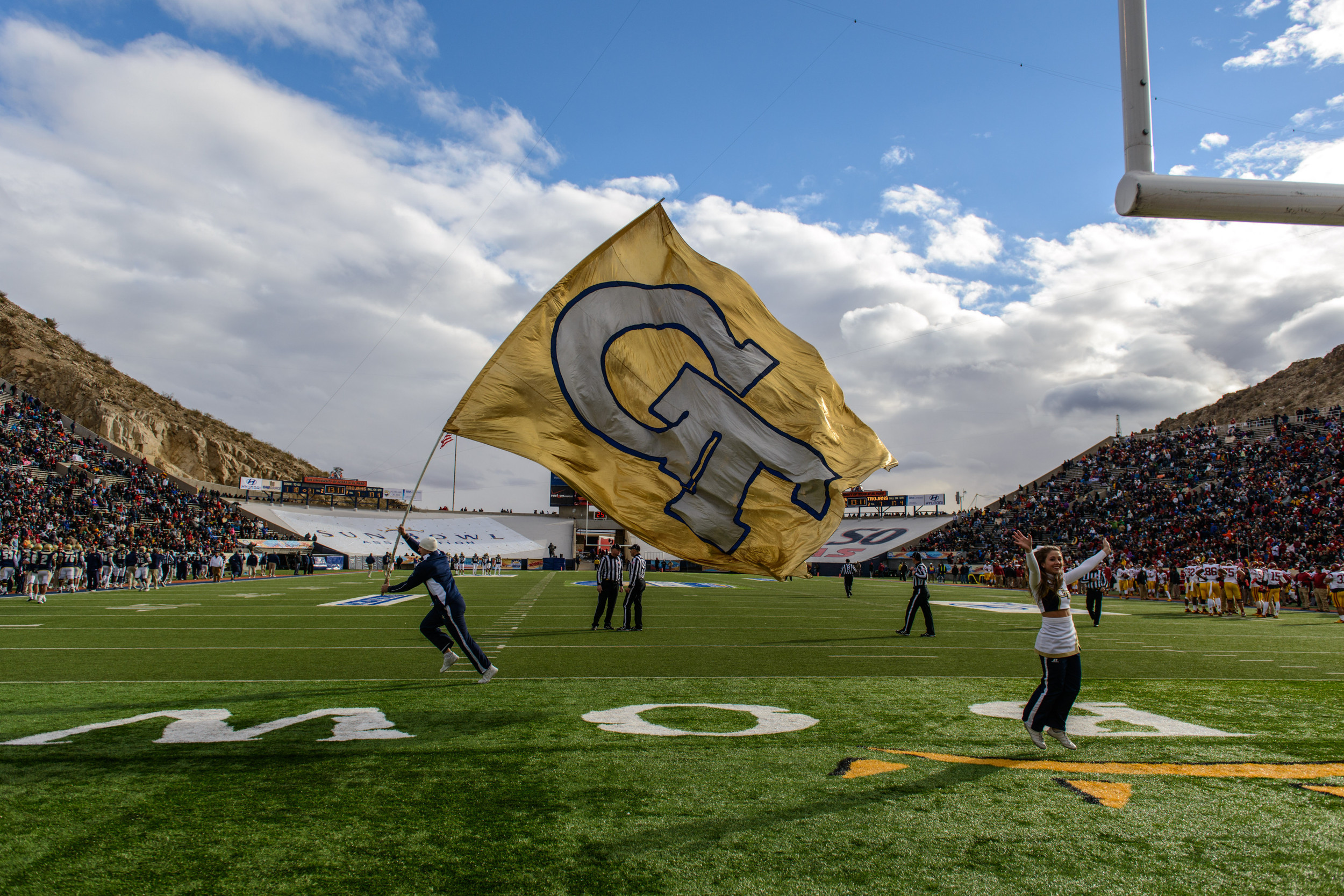 The GT Cheerleaders run the GT flag in the endzone after a touchdown.