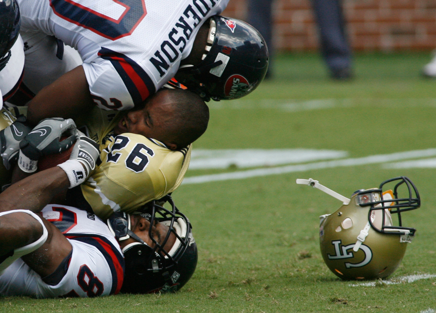Samford Georgia Tech cornerback Dominque Reese (26) is sandwiched by Samford wide receiver Jeff Moore, bottom, and Ryan Anderson after Reese lost his helmet recovering a fumble during the second quarter of their football game, Saturday, Sept. 8, 2007, in Atlanta. (AP Photo/John Amis)